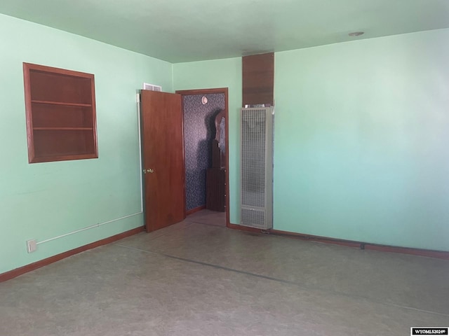 unfurnished room featuring visible vents, baseboards, and a heating unit