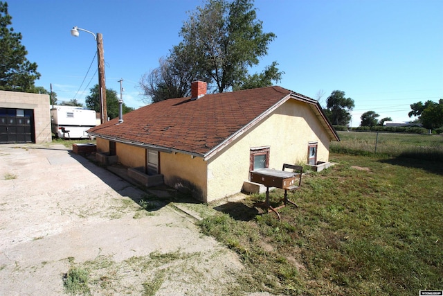 213 10th Ave, Lyman, NE 69352 - view of home's exterior with a chimney, stucco siding, a yard, fence, and an outbuilding