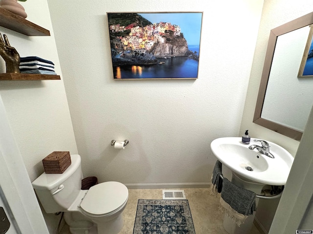 bathroom featuring toilet, sink, and tile patterned flooring