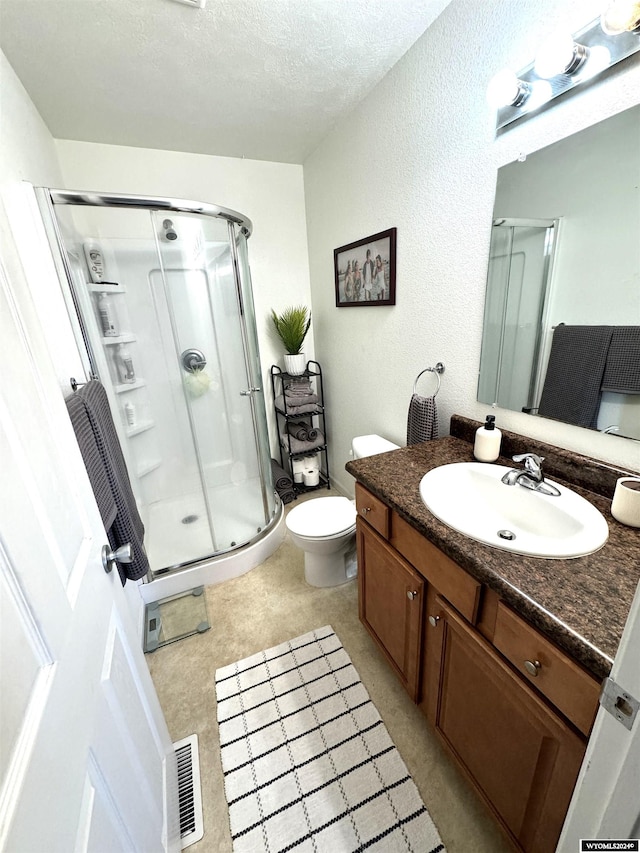 bathroom featuring a textured ceiling, a shower with shower door, toilet, and vanity