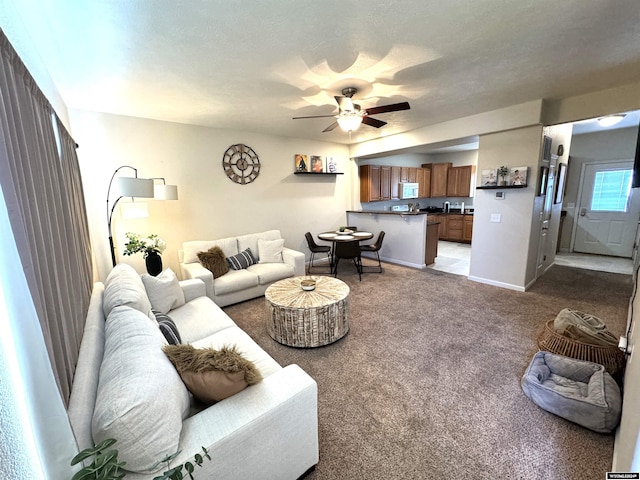 living room featuring a textured ceiling, ceiling fan, and carpet flooring