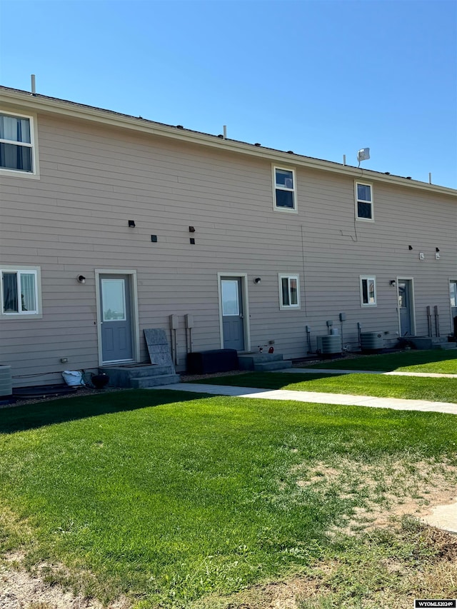 rear view of property featuring a yard and central air condition unit