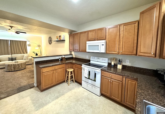 kitchen featuring light colored carpet, ceiling fan, white appliances, and kitchen peninsula