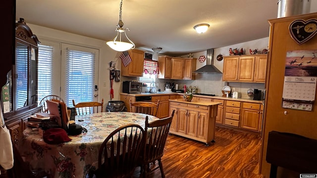 kitchen with hanging light fixtures, a center island, sink, dark hardwood / wood-style floors, and wall chimney exhaust hood