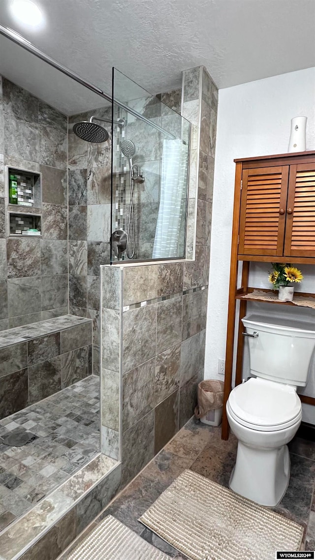 bathroom with toilet, tiled shower, and tile patterned flooring