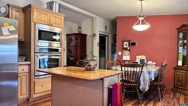 kitchen featuring dark hardwood / wood-style flooring, a kitchen bar, stainless steel appliances, and light brown cabinets