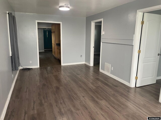 unfurnished bedroom featuring ensuite bath and dark wood-type flooring