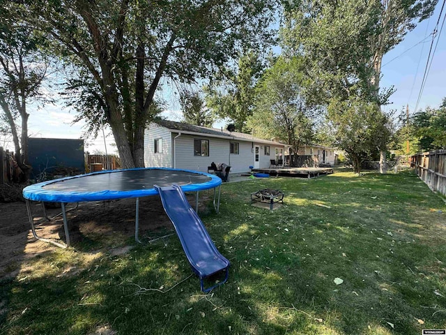 view of yard featuring a trampoline and a deck