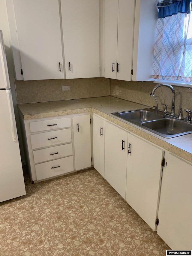 kitchen with white fridge, sink, and white cabinetry