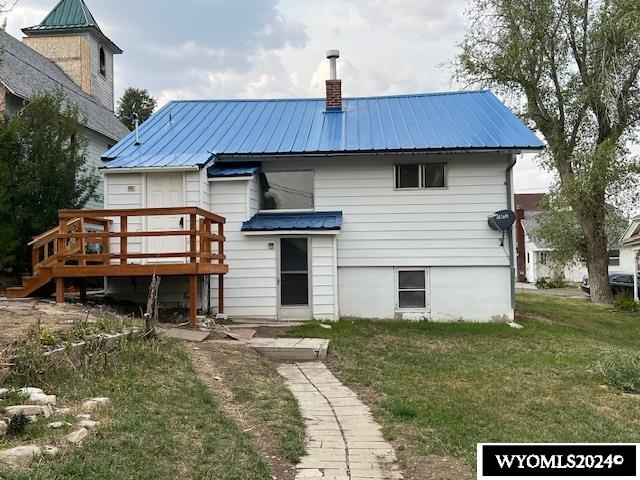 back of house featuring a lawn and a deck