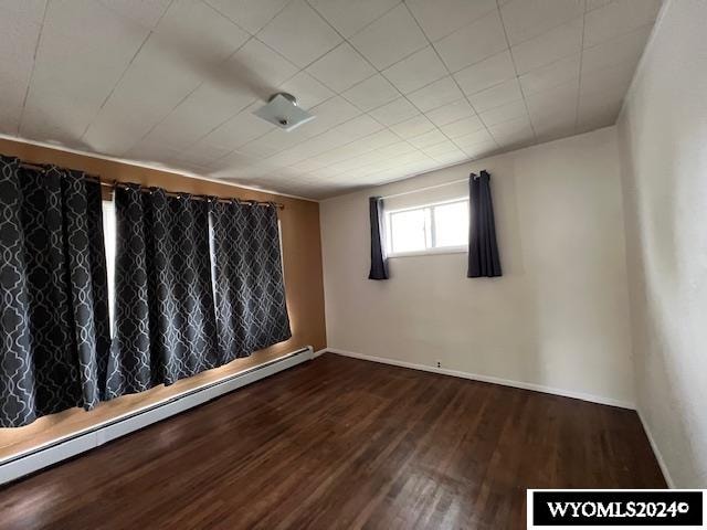 empty room featuring baseboard heating and hardwood / wood-style floors