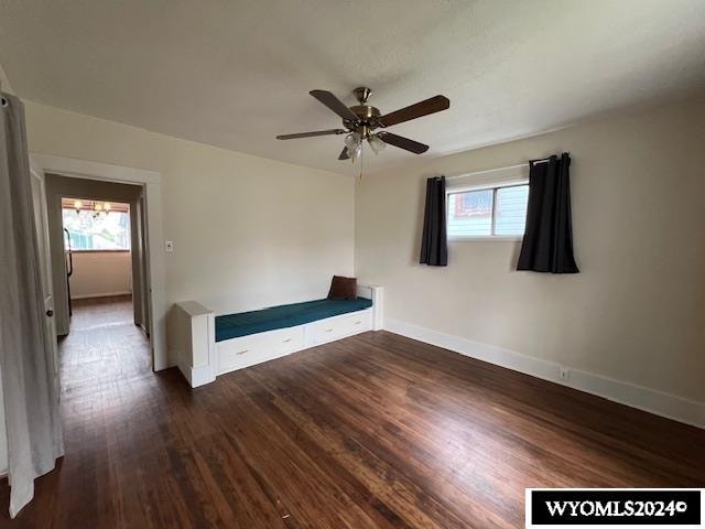 unfurnished bedroom featuring multiple windows, dark hardwood / wood-style flooring, and ceiling fan