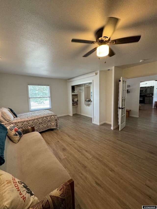 living room with a textured ceiling, hardwood / wood-style flooring, and ceiling fan