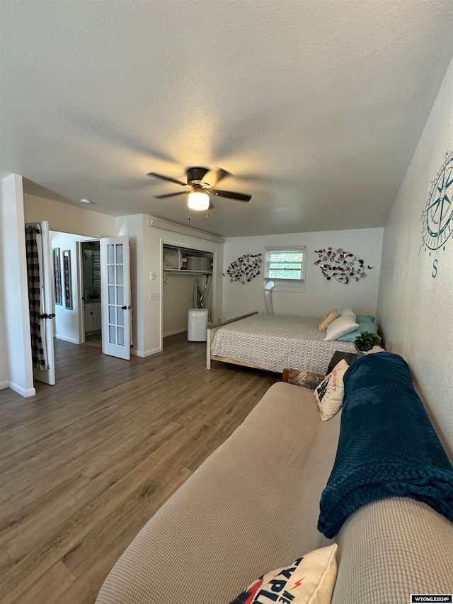 bedroom with a textured ceiling, ceiling fan, a closet, and dark hardwood / wood-style flooring