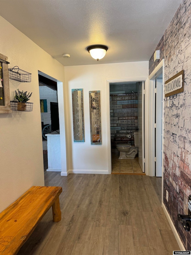 hall featuring brick wall, a textured ceiling, and hardwood / wood-style floors