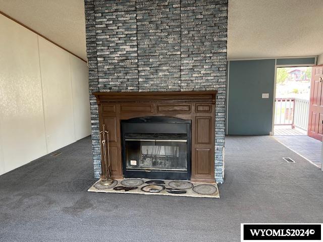156 Elm St, Kemmerer, WY 83101 - detailed view of carpet flooring, a glass covered fireplace, and a textured ceiling