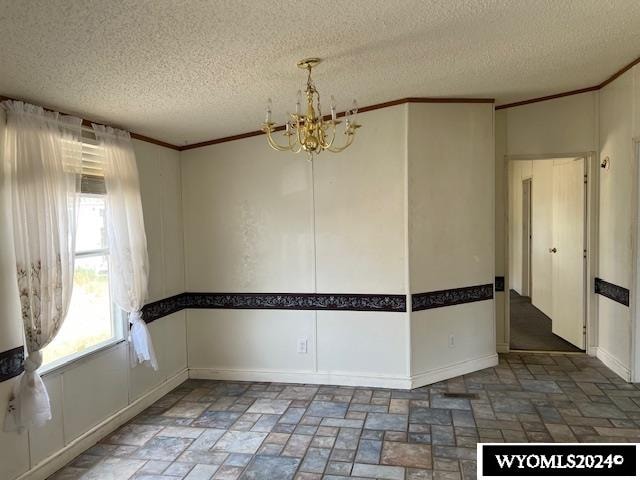 spare room with a textured ceiling, ornamental molding, and a chandelier