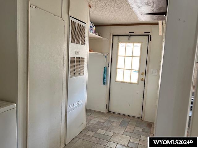 156 Elm St, Kemmerer, WY 83101 - doorway with a heating unit, stone finish floors, washer / dryer, and a textured ceiling