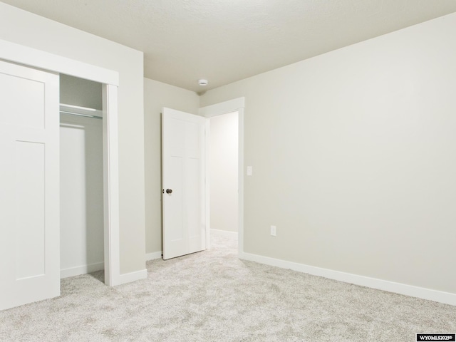 unfurnished bedroom featuring light colored carpet and a closet