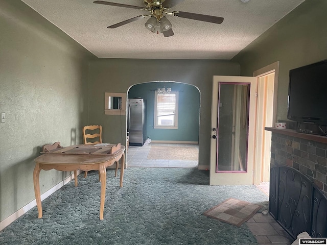 interior space with ceiling fan, a brick fireplace, and a textured ceiling