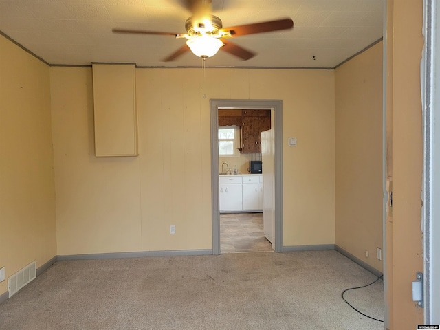 unfurnished room featuring ceiling fan, sink, and light colored carpet