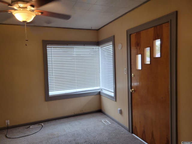 carpeted entrance foyer featuring a healthy amount of sunlight and ceiling fan