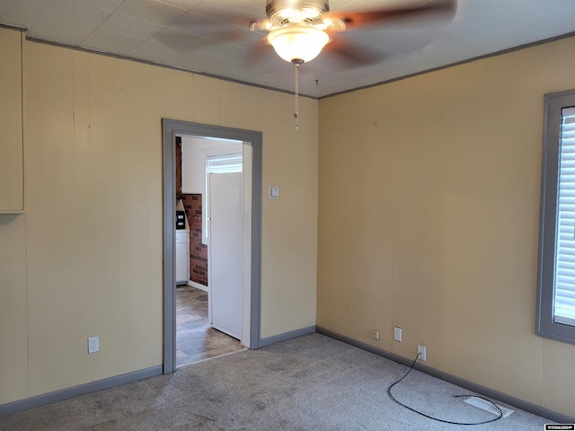 carpeted empty room featuring ceiling fan and wooden walls