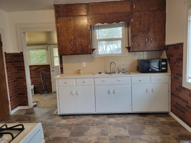 kitchen featuring white cabinetry, brick wall, sink, and white range