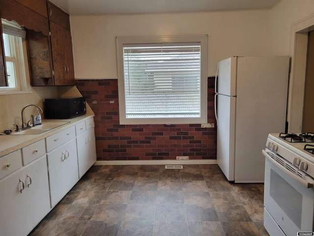 kitchen featuring sink, white cabinetry, and white appliances