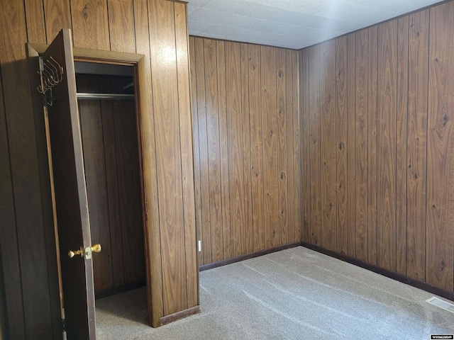 carpeted empty room with wood walls