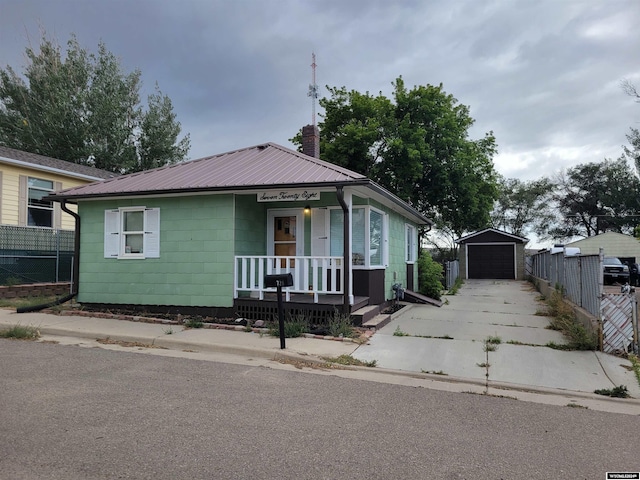 bungalow-style house with a garage, an outbuilding, and a porch