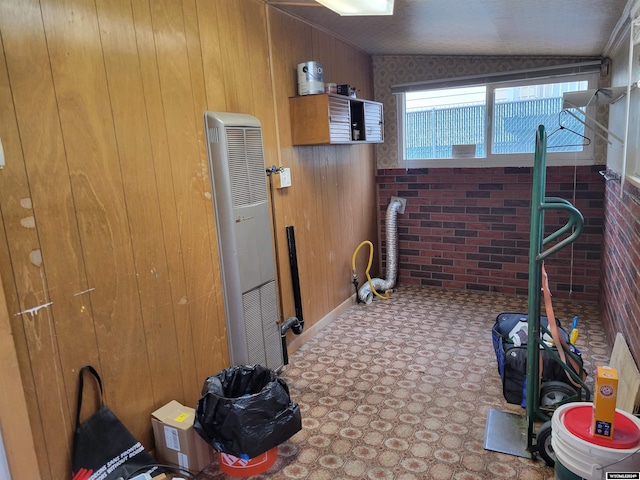 interior space with wooden walls, brick wall, and vaulted ceiling