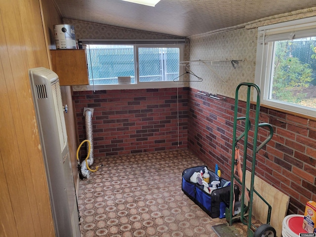 bathroom featuring brick wall and lofted ceiling