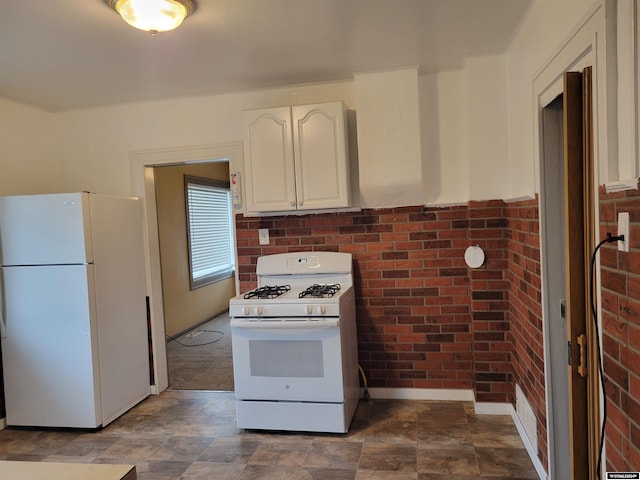 kitchen with dark carpet, brick wall, white cabinetry, and white appliances