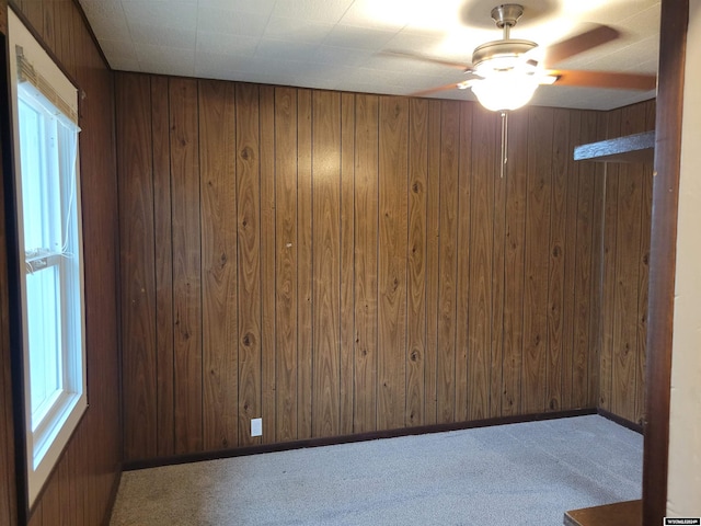 carpeted spare room featuring ceiling fan and wooden walls