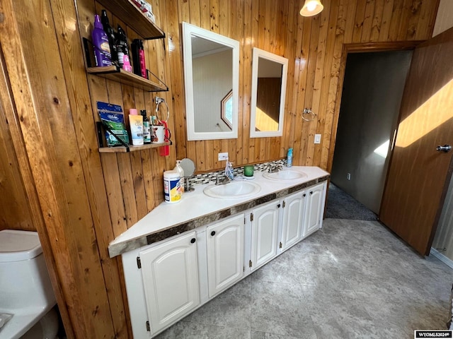 bathroom with vanity, toilet, and wooden walls