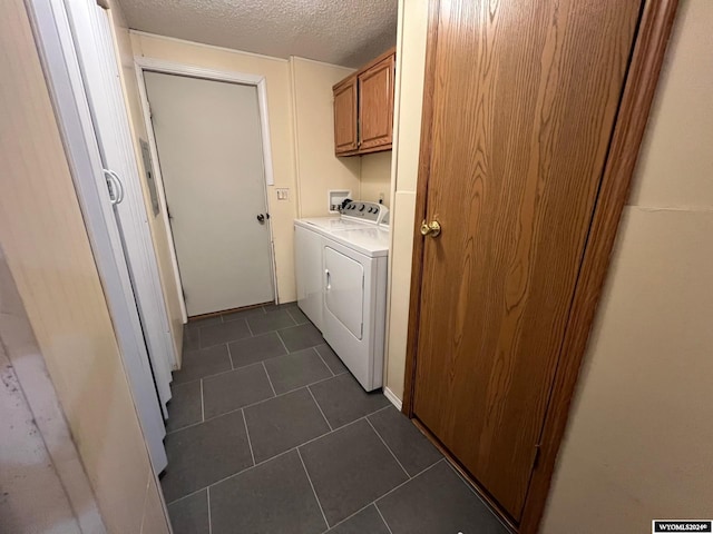 laundry area featuring dark tile patterned flooring, a textured ceiling, cabinets, and separate washer and dryer