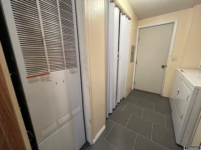 clothes washing area with dark tile patterned flooring, a textured ceiling, and washer and dryer