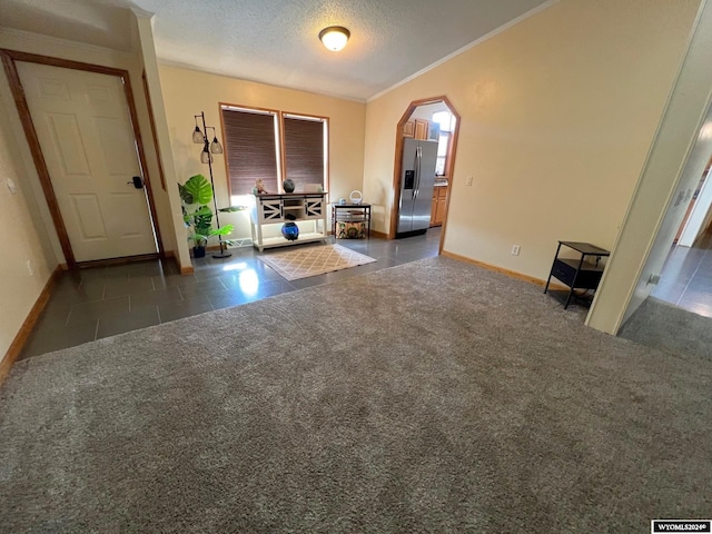 interior space with crown molding, a textured ceiling, a wealth of natural light, and dark colored carpet