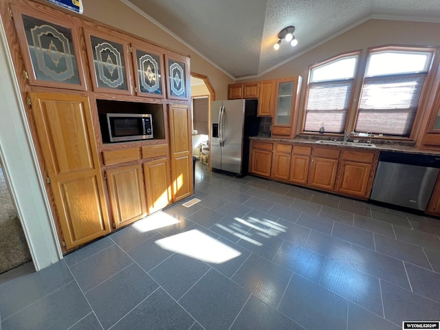 kitchen with crown molding, dark tile patterned flooring, lofted ceiling, and stainless steel appliances