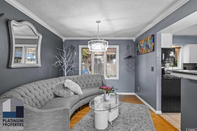 living room featuring crown molding, light wood-type flooring, a textured ceiling, and a chandelier