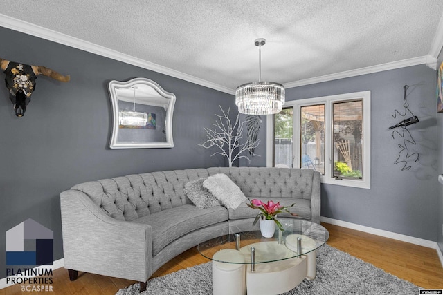 living room featuring a textured ceiling, wood-type flooring, ornamental molding, and an inviting chandelier