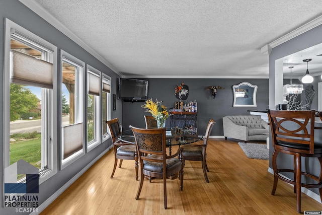 dining area featuring hardwood / wood-style floors, a textured ceiling, ornamental molding, and a notable chandelier