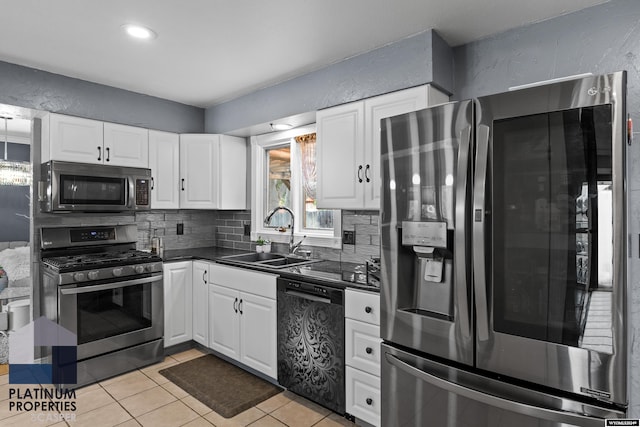 kitchen featuring tasteful backsplash, stainless steel appliances, sink, white cabinets, and light tile patterned flooring