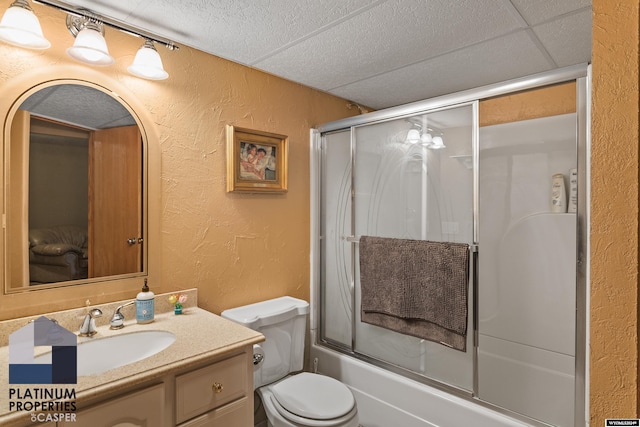 full bathroom with combined bath / shower with glass door, vanity, toilet, and a drop ceiling