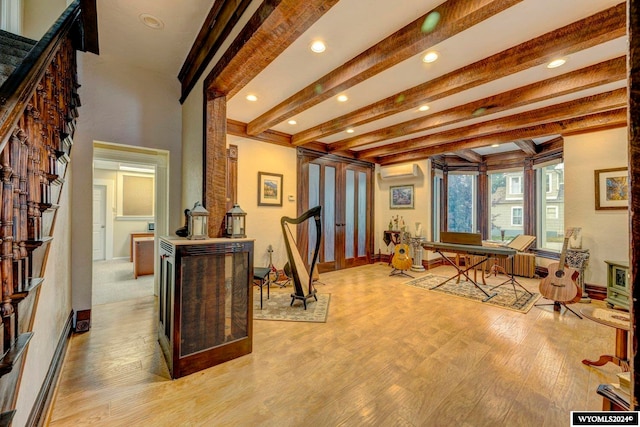 interior space with a wall unit AC, beamed ceiling, and light hardwood / wood-style flooring