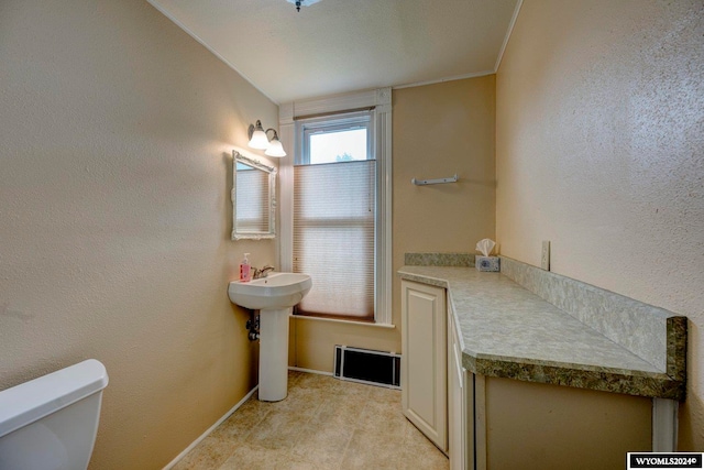 bathroom with toilet, crown molding, and sink