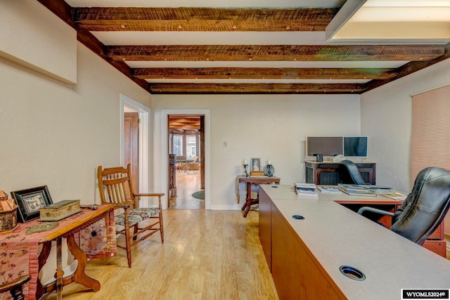 home office featuring light wood-type flooring and beam ceiling