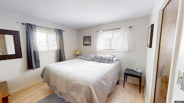 bedroom featuring light hardwood / wood-style floors, multiple windows, and a textured ceiling