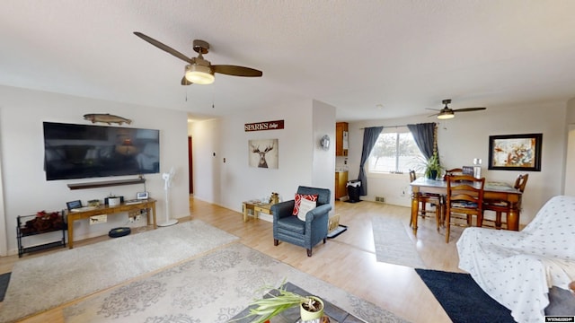 living room featuring a textured ceiling, ceiling fan, and light hardwood / wood-style flooring